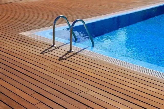 A swimming pool with a wooden deck and stairs