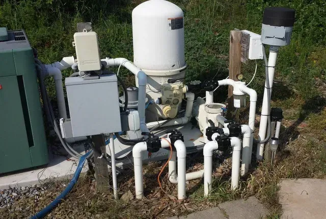 A bunch of pipes are sitting on the ground next to a green box