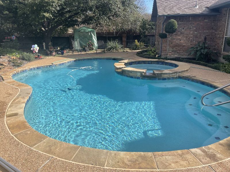 A large swimming pool with a hot tub in the backyard of a house.