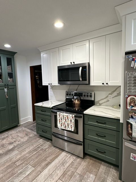 Kitchen with green cabinets, a stove, a microwave, and a refrigerator