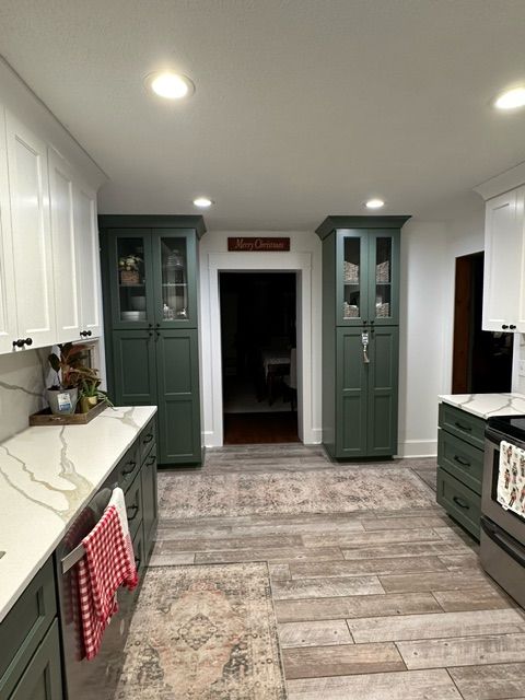 Kitchen with green cabinets, white counter tops, and stainless steel appliances