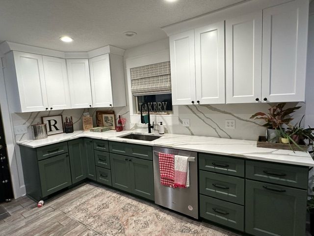 A kitchen with green cabinets and white cabinets and a stainless steel dishwasher