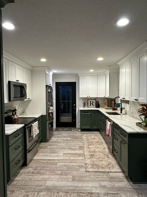 Kitchen with green cabinets, white cabinets and stainless steel appliances