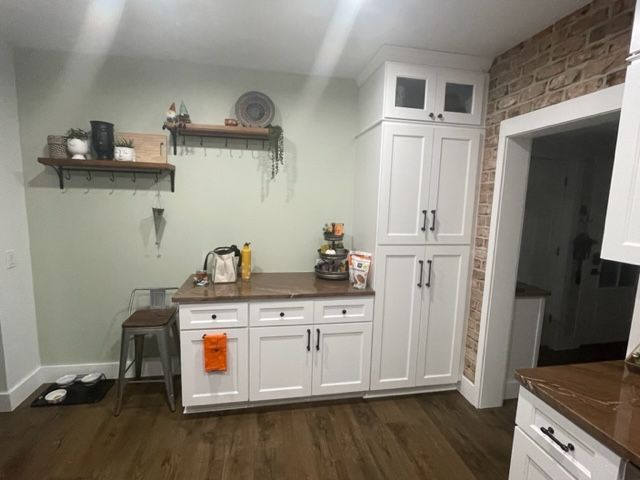 A kitchen with white cabinets and a brick wall