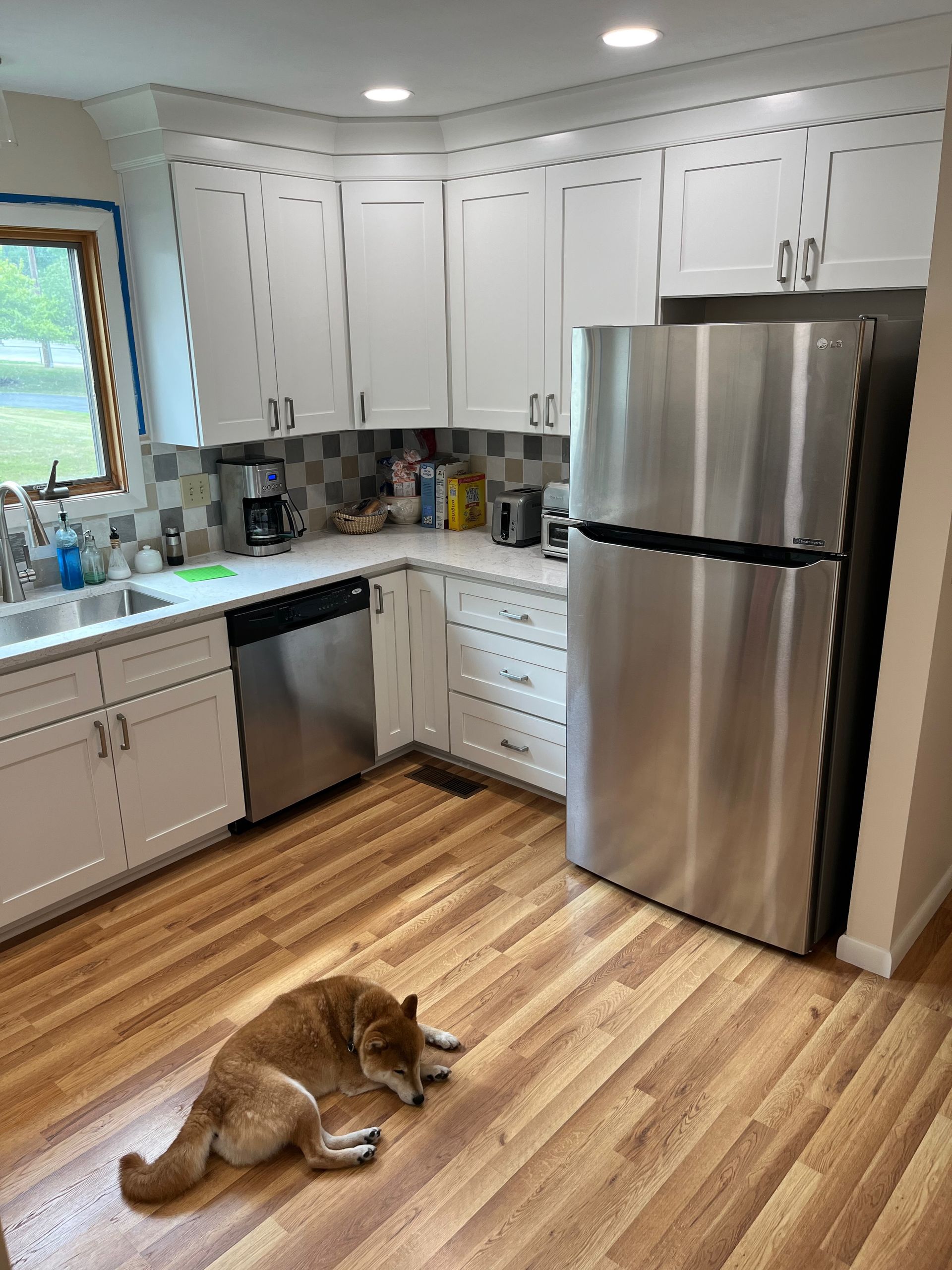 A dog is laying on the floor in a kitchen next to a refrigerator