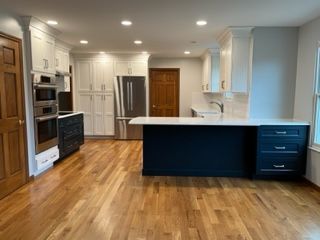 A kitchen with hardwood floors, white cabinets, stainless steel appliances and a large island