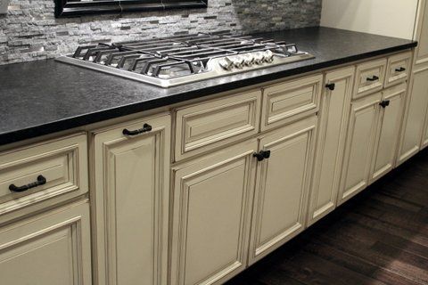 A kitchen with white cabinets and black countertop and a stove top oven