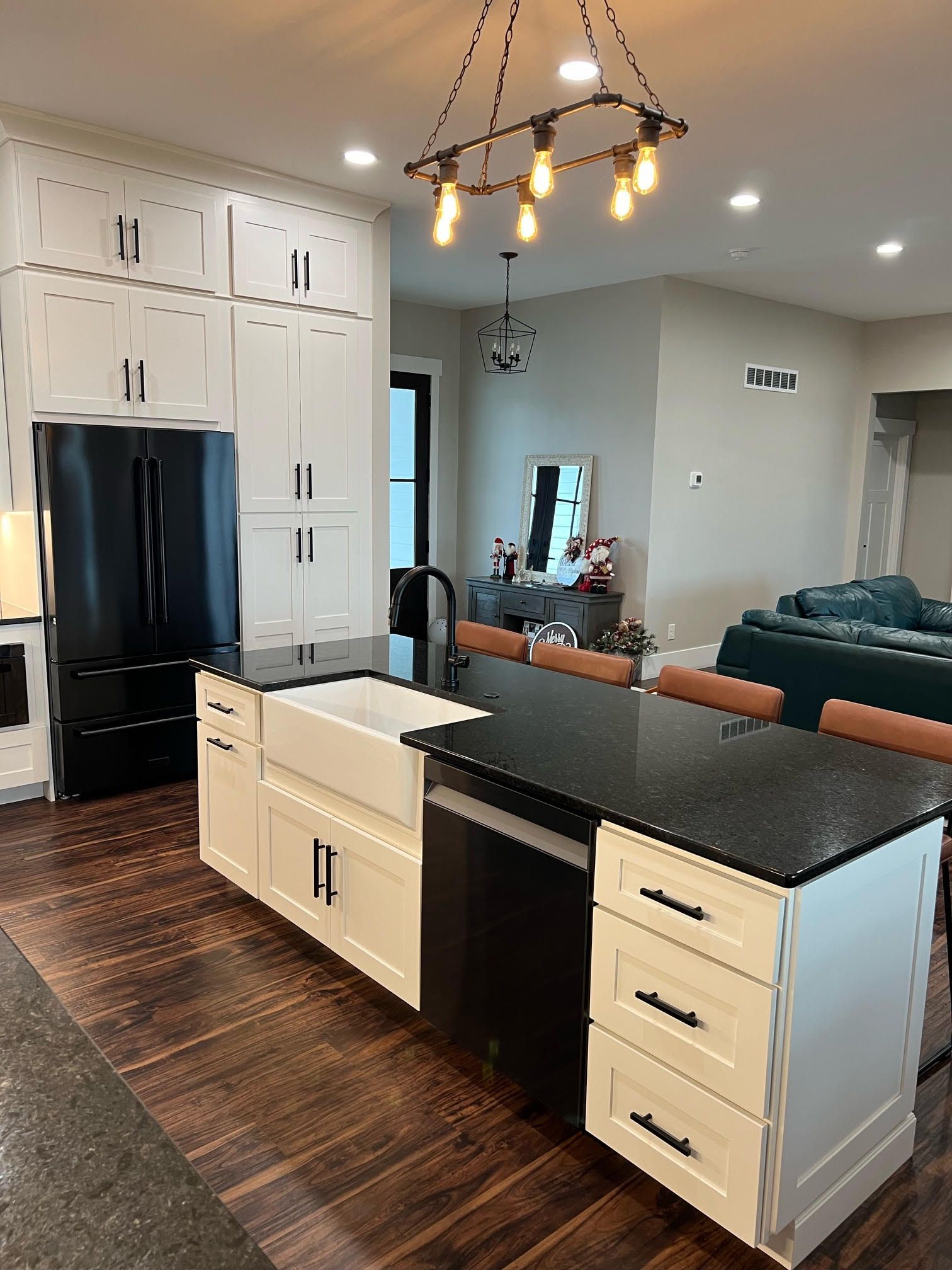 Kitchen with white cabinets, black countertop, a sink, a refrigerator, and a dishwasher 