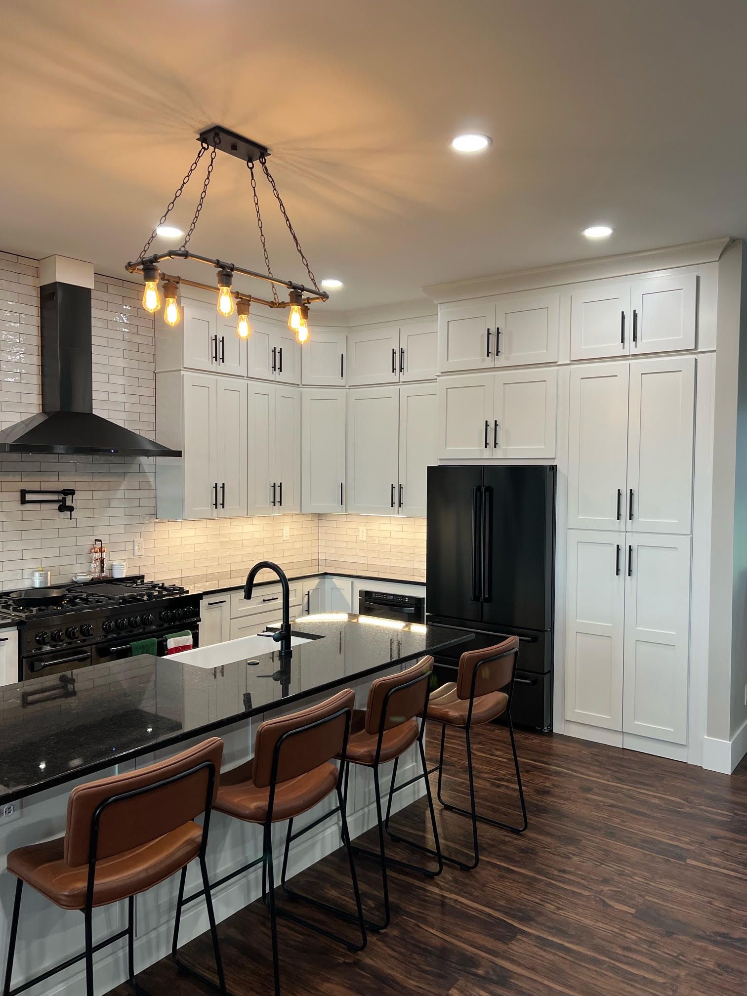 Kitchen with white cabinets, a black refrigerator and a large island