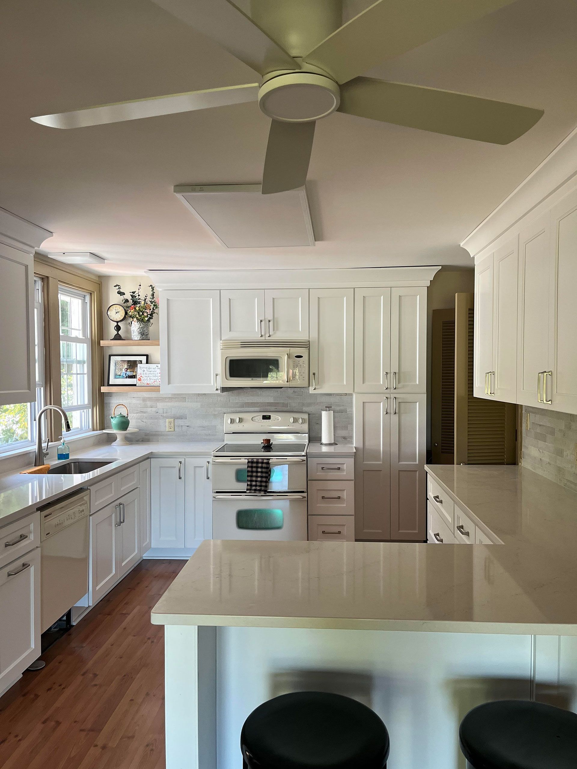 A kitchen with white cabinets and a ceiling fan