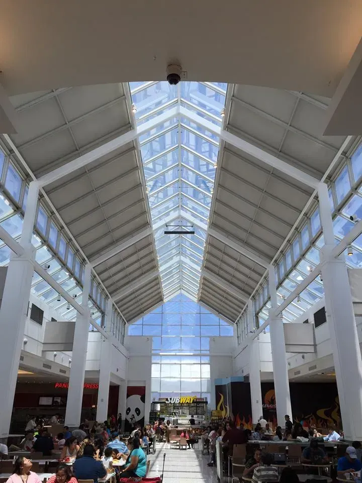 Mall interior with a high, glass ceiling and skylights, food court, people dining.