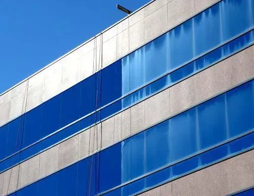Blue-tinted windows on a modern building, with horizontal concrete panels against a clear blue sky.