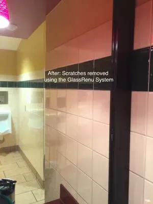 Public restroom interior with white tiled walls and a black support beam, after scratch removal.