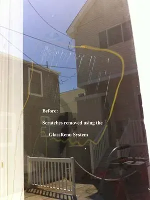 Scratched glass before repair, reflecting buildings, and a yellow hose.