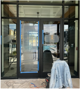 Exterior doors with blue tape, likely under construction. Jacket and equipment in foreground.