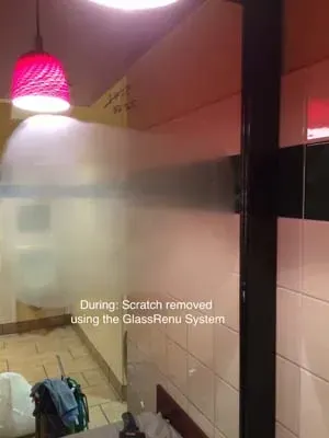 Frosted glass door with a scratch removed using the GlassRenu System, in a room with a red light fixture.