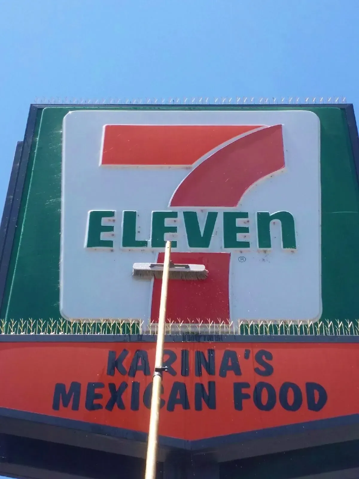 7-Eleven sign with Karina's Mexican Food below, against a blue sky.