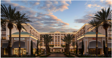 Hotel exterior with palm trees under a sunset sky.