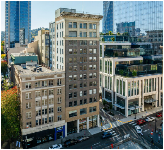 Multi-story buildings on a city street; Bank sign, cars, and other modern buildings in the background.