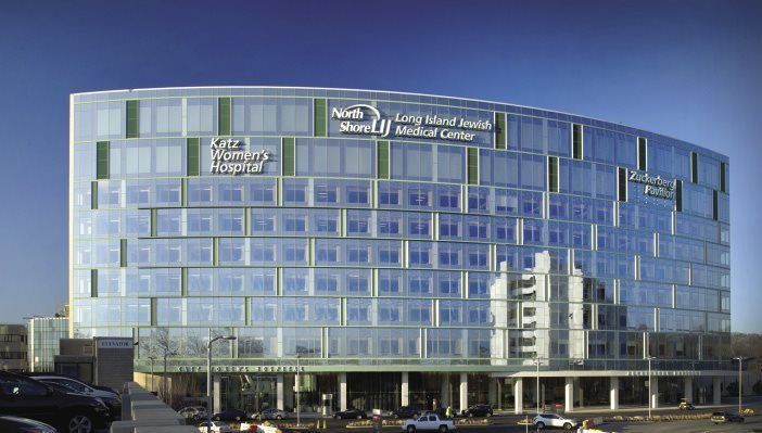 Glass-walled hospital building under a blue sky, with signage for Northwell and LIJ Medical Center.