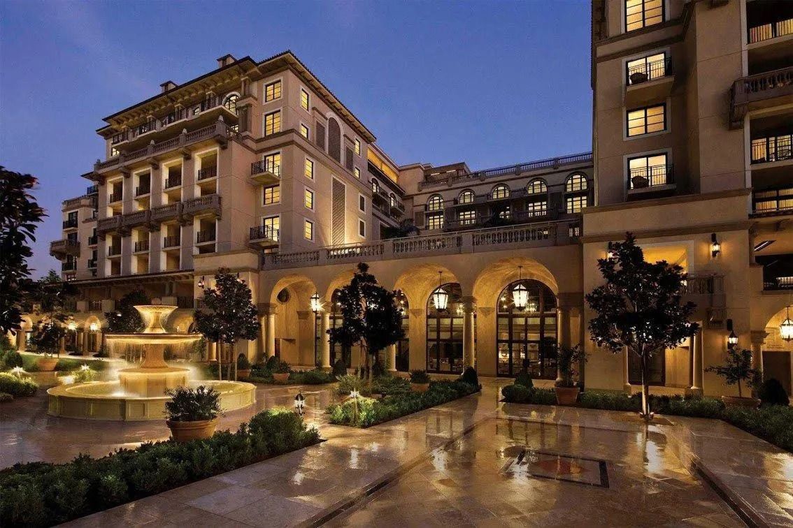 Elegant hotel exterior at dusk with fountain and arched entrance.