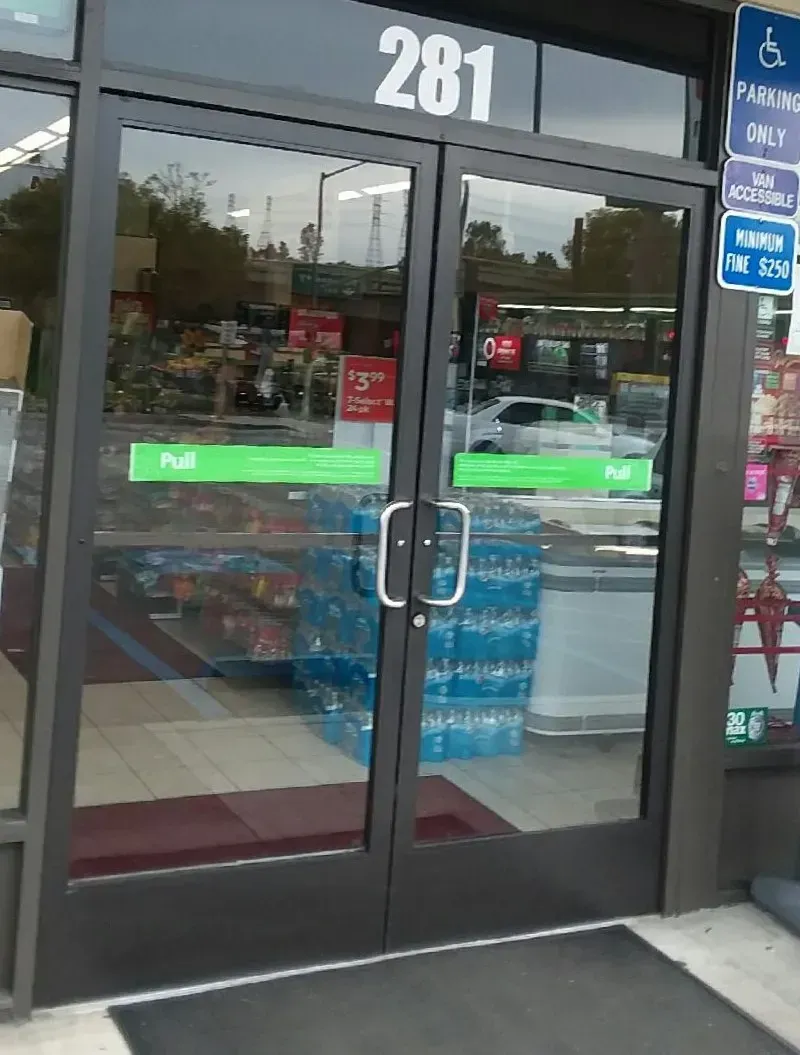 Glass doors with the number 281 above them, leading into a store. Sign indicates accessible parking.