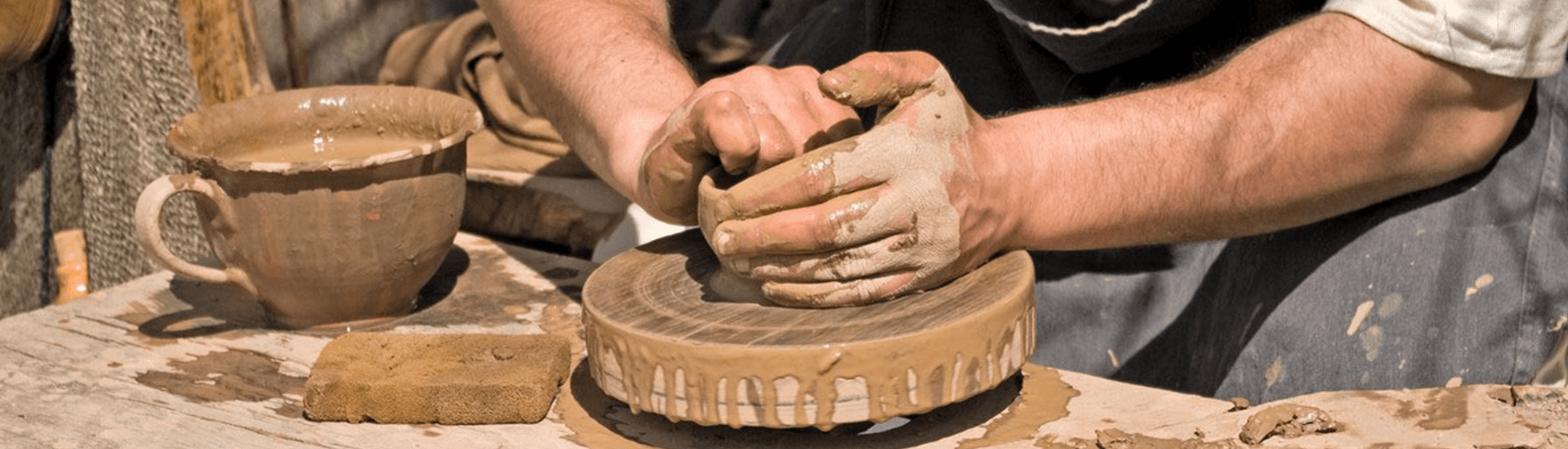 A man is making a pot on a pottery wheel.