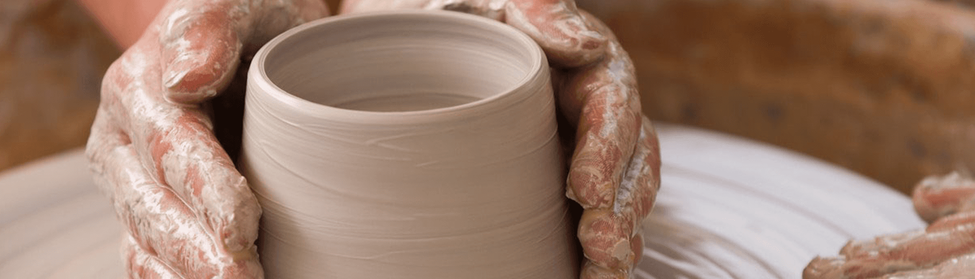 A person is making a vase out of clay on a pottery wheel.