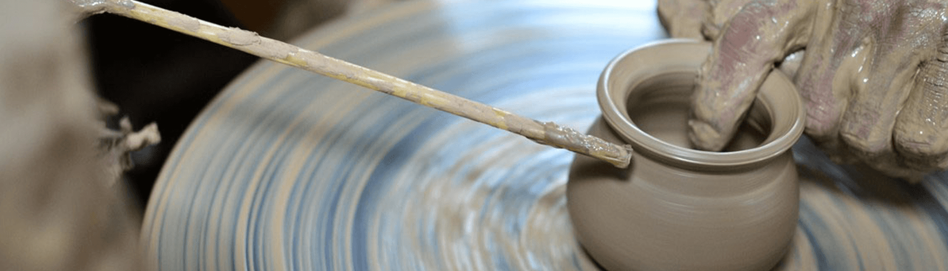 A person is making a vase on a pottery wheel.