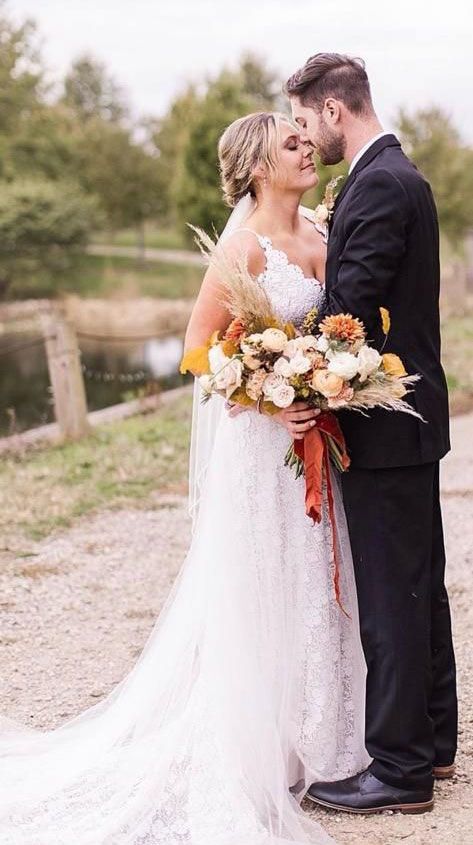 A bride and groom are kissing while holding a bouquet of flowers