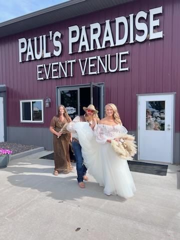 A bride and groom are standing in front of Paul 's Paradise event venue