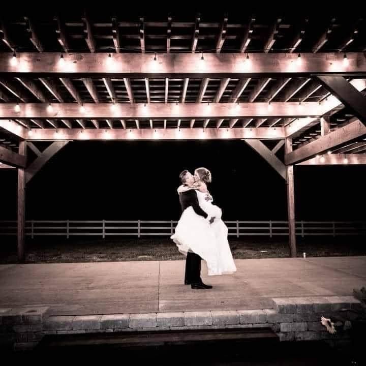 A bride and groom are kissing under a gazebo at night