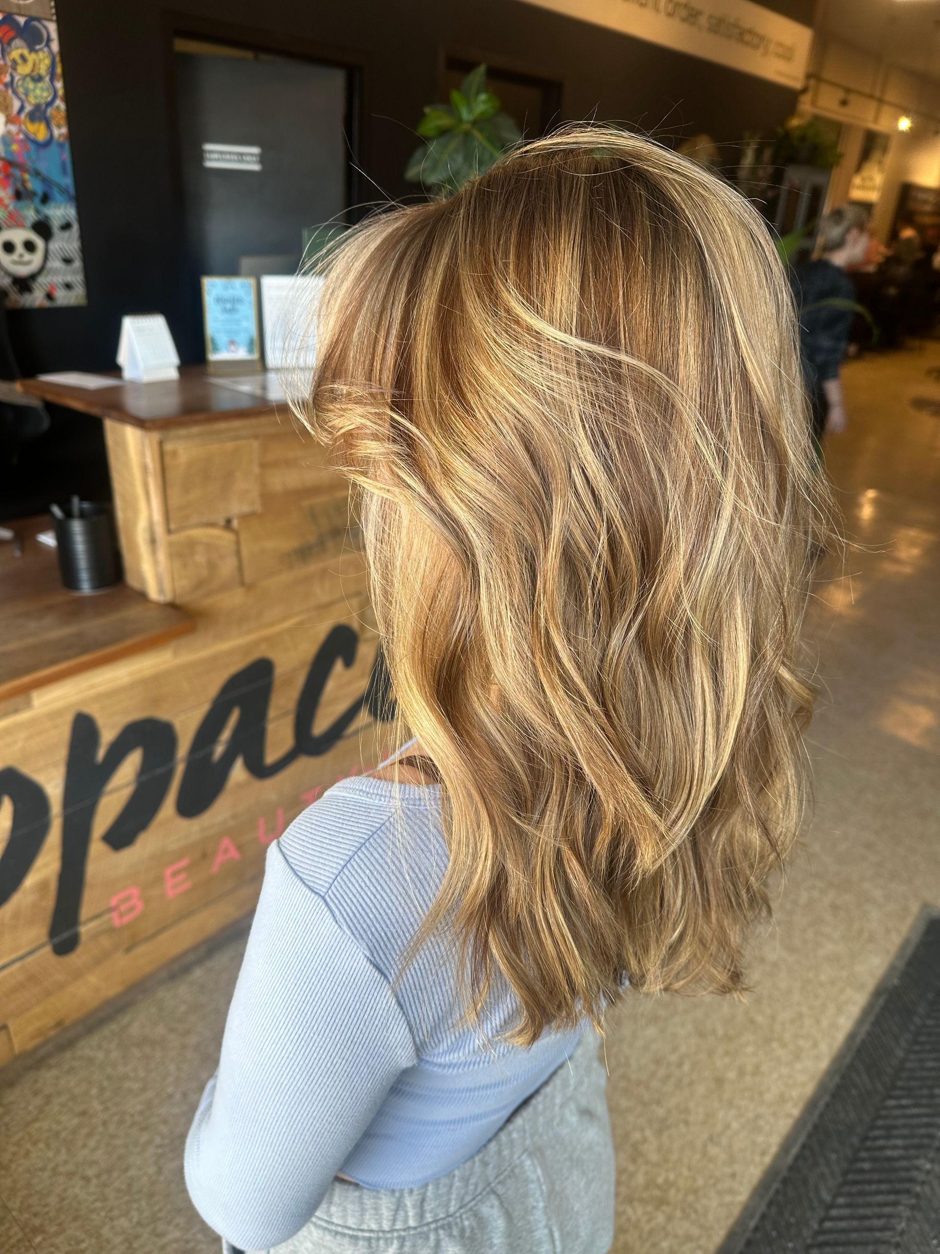 Long, wavy red hair cascading down a person's back; they are wearing a gray sweater.