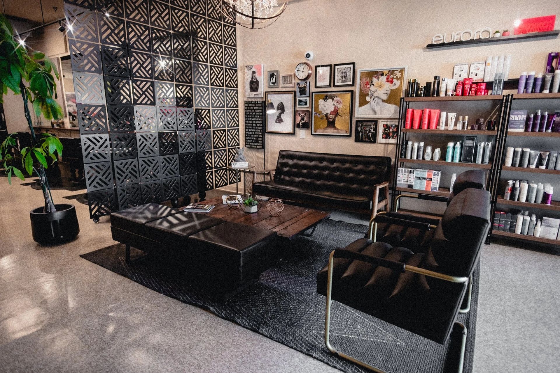 Stylish salon waiting area with black leather furniture, decor, and product shelves.
