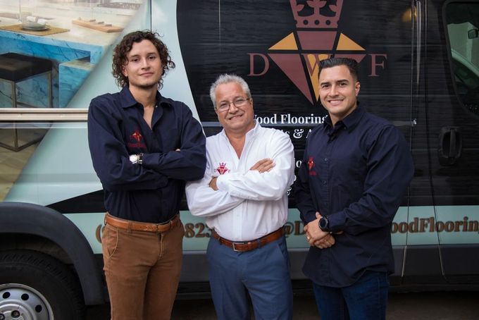 Three men are posing for a picture in front of a van.