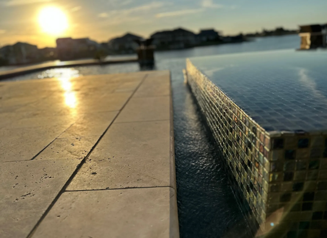 Infinity pool edge overlooking water at sunset.