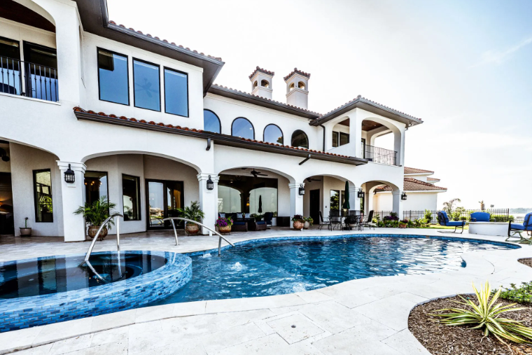 Luxury white house with pool, arched windows, and tiled roof.