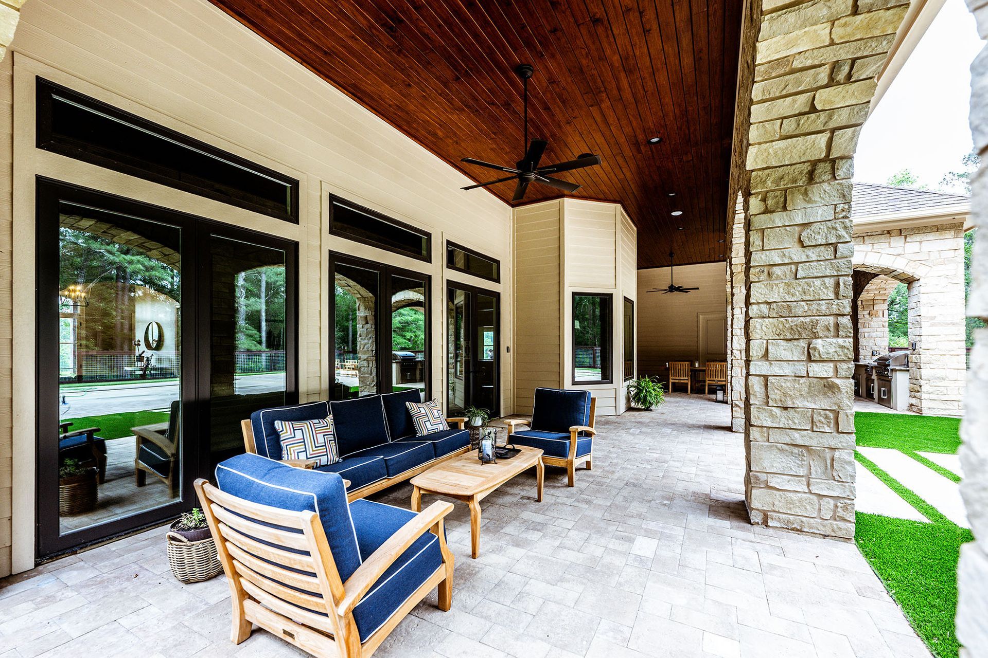 Patio with blue seating, wooden ceiling, and stone columns.