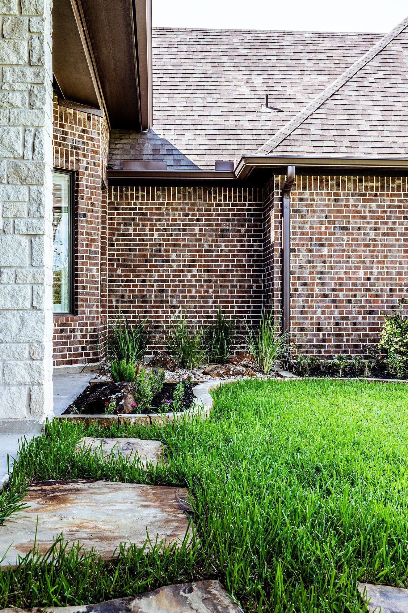 Brick house exterior with stone steps leading to the entrance green grass and landscaping.