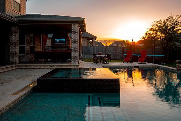 Pool and patio area at sunset pool reflects sky.