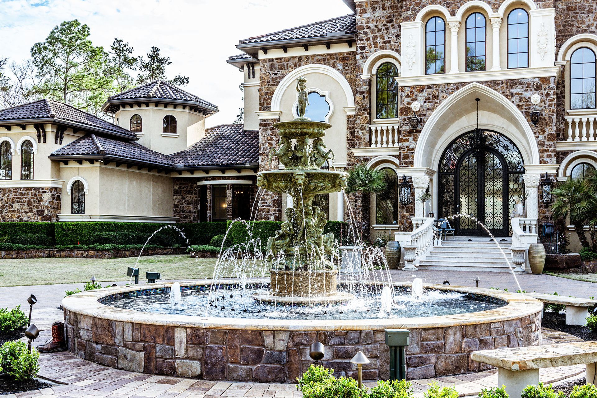 A grand stone mansion with a large fountain in front.