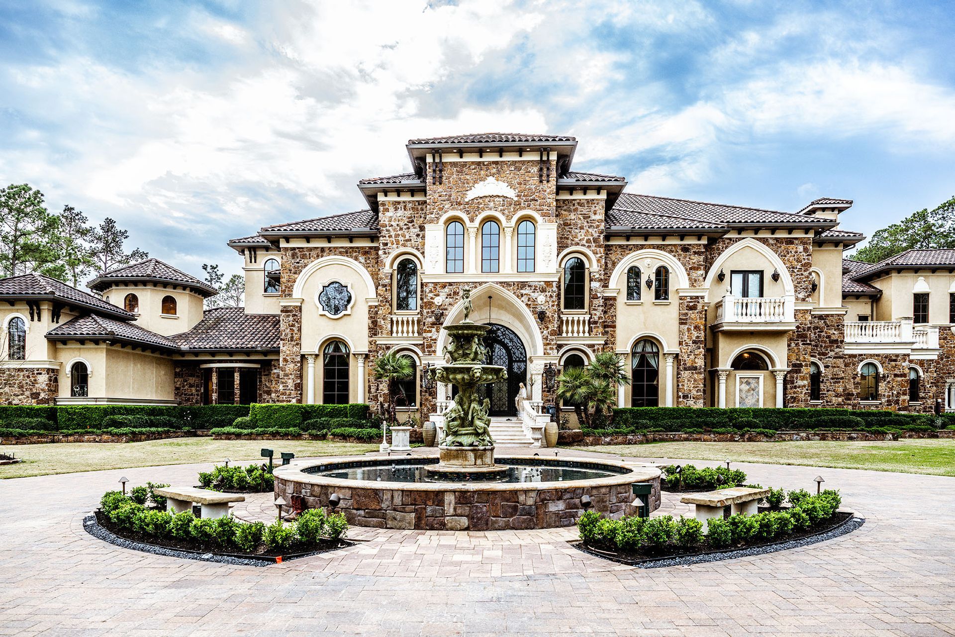 A grand stone mansion with fountain in front.