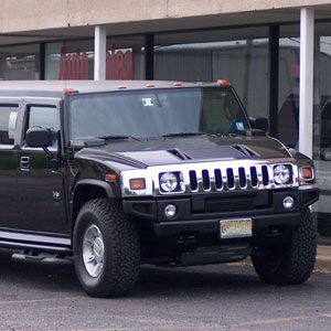 A black hummer is parked in front of a building.