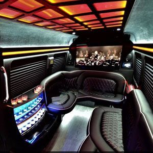 The inside of a limousine with a large screen on the ceiling