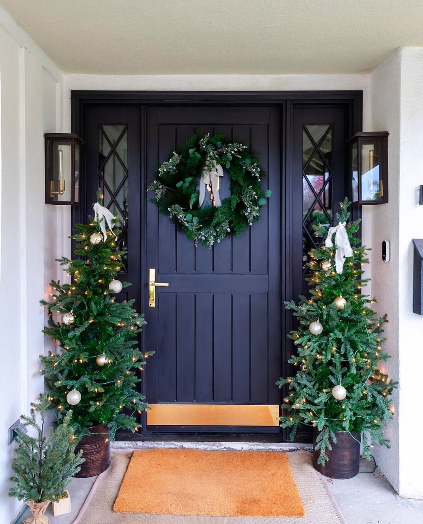 The front door of a house is decorated with christmas trees and a wreath.