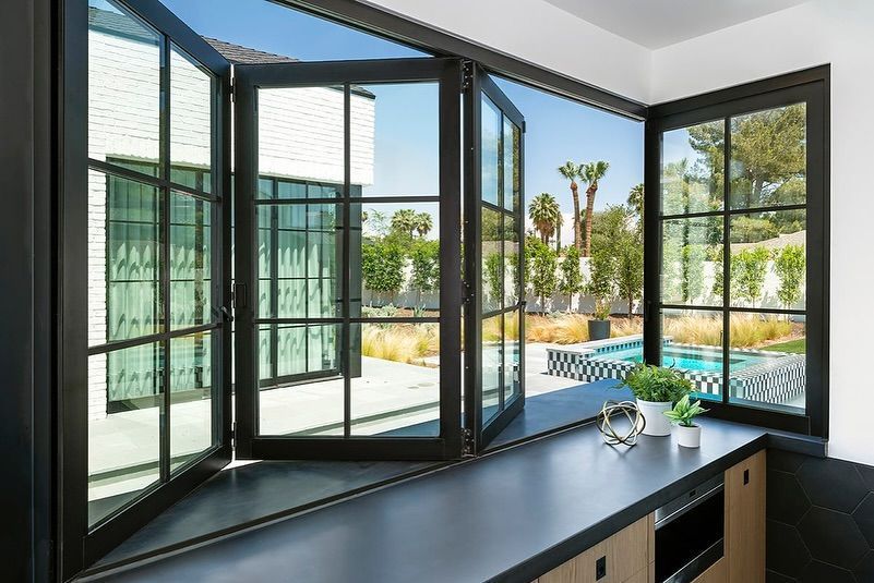 A kitchen with a lot of windows and a swimming pool in the background.