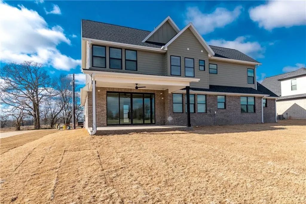 A large house with a lot of windows is sitting on top of a dirt field.
