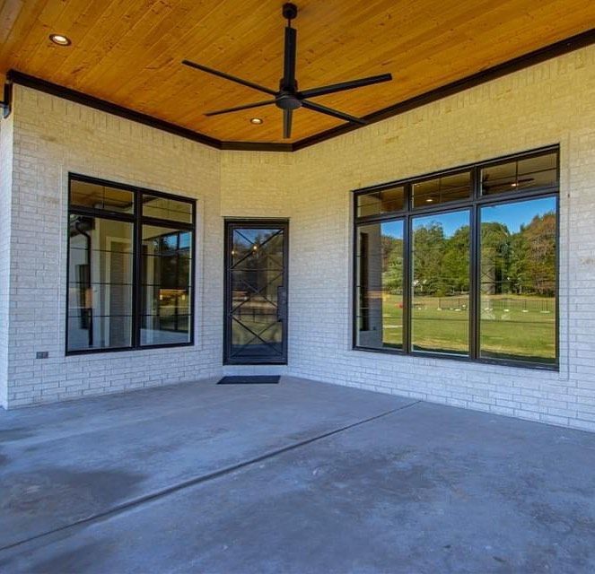 A large patio with a ceiling fan and lots of windows.