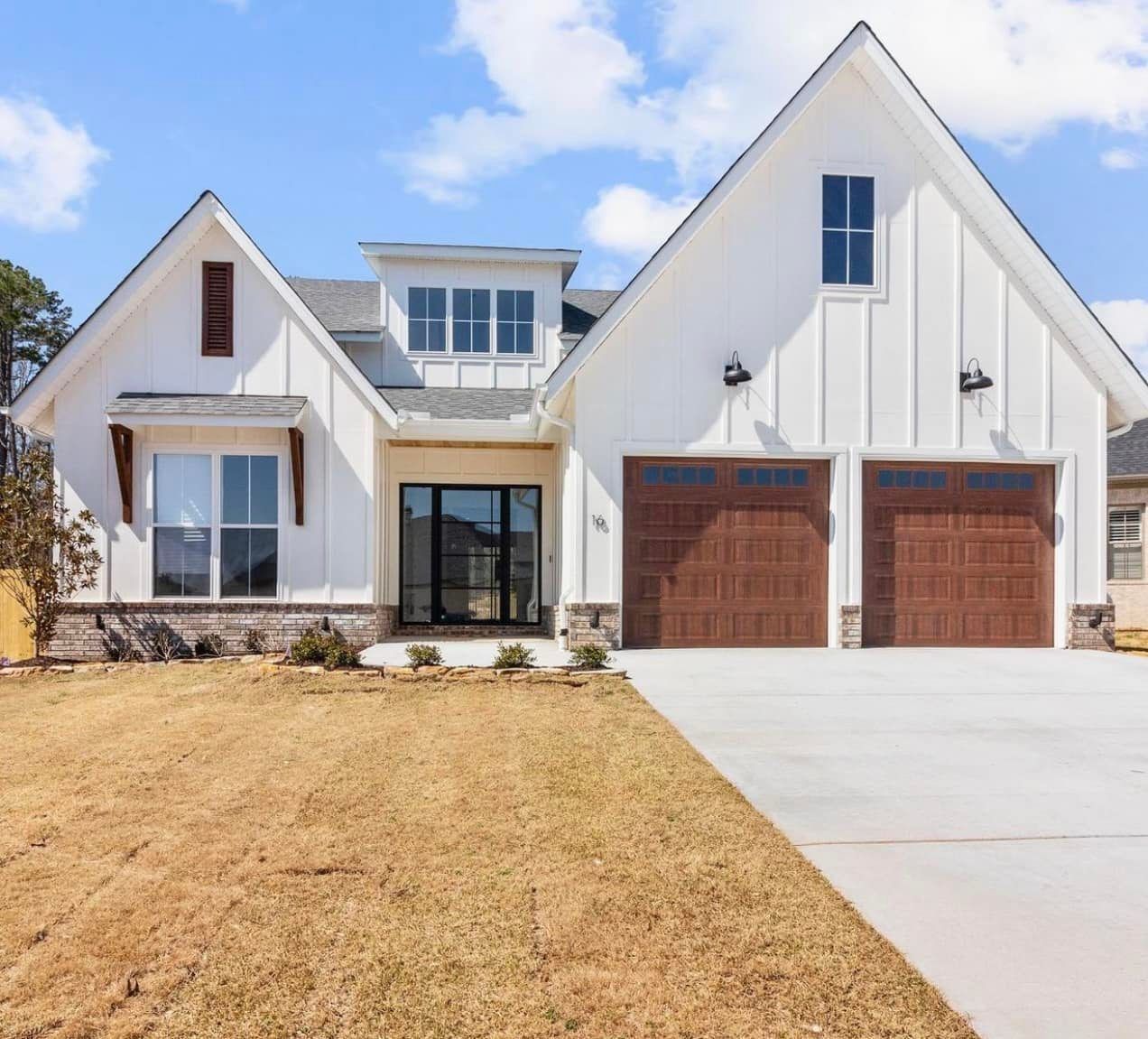 A white house with two garage doors and a concrete driveway