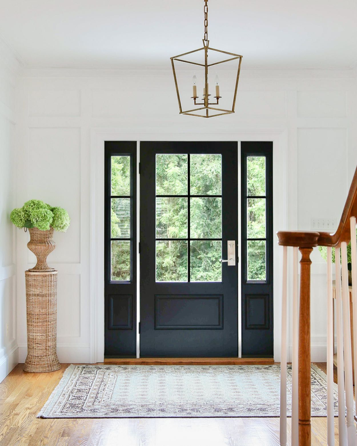A hallway with a black door and a staircase